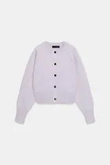 Chaqueta corta de punto color lila, con cuello redondo, manga larga con puños acanalados y cierre frontal con botones negros. Presenta un diseño con acabado en rib en el ruedo.