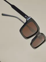 Lentes de sol rectangulares negros con lentes marrones.