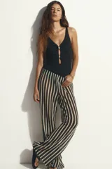 Malla enteriza de color negro con escote en V, tirantes ajustables y copas con relleno extraíble. Cuenta con diseño cut-out frontal decorado con herrajes metálicos dorados, corte de pierna alto y espalda de cobertura media.