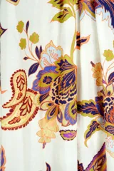 Vestido largo con tirantes finos, escote redondo y falda amplia con volado en el ruedo. Presenta un estampado botánico tipo paisley en tonos cálidos sobre fondo claro.