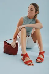 Sandalias bajas de cuero negro con tachas plateadas, tiras cruzadas y hebilla al tobillo.