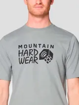 Remera de manga corta color gris con cuello redondo. Presenta un estampado gráfico en el centro del pecho con el logo y nombre de la marca Mountain Hardwear en color negro.