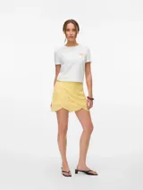 Short pollera color amarillo pálido con bordado de puntilla, corte mini y cierre lateral oculto.