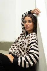 Saco de punto con diseño combinado de estampado animal print en el cuerpo y rayas horizontales en las mangas. Presenta cuello redondo, cierre frontal con botones y terminaciones en tejido acanalado negro.