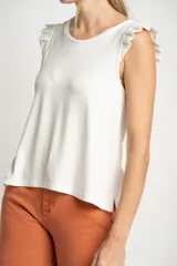 Musculosa negra de viscosa con cuello redondo y detalle de volados en los hombros. Presenta un corte holgado y fluido con un pequeño aplique metálico en el ruedo.