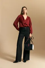 Blusa negra de satén con escote en V y detalle de volados frontales. Presenta mangas largas con puños abotonados y una silueta fluida.