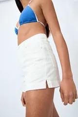 Short blanco de algodón con elastano, calce medio, bolsillos funcionales y tajos pequeños en el ruedo.