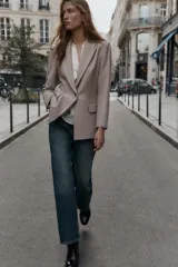 Blazer de corte sastrero confeccionado en tejido de lana con diseño de espiga. Presenta cuello con solapas, hombreras, cierre frontal con un botón y bolsillos delanteros con solapa.