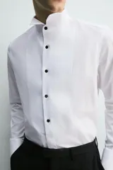 Camisa slim fit de algodón con cuello smoking, manga larga con puño doble para gemelos y pechera combinada a tono con cierre frontal de botones.