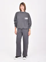 Buzo gris oscuro con efecto acid wash, cuello redondo, mangas largas y pequeño estampado blanco en el pecho con texto y motivos florales.