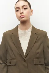 Blazer color marrón con solapas de muesca, cierre frontal con un botón, bolsillos de solapa y mangas largas.