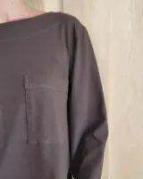 Remera de manga larga color marrón chocolate, con cuello redondo y dos bolsillos frontales tipo parche.