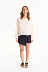 Blusa de viscosa color blanco con escote en V y cordón ajustable, mangas largas y volados decorativos en los hombros.