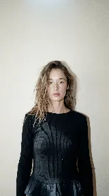 Remera de manga larga al cuerpo, confeccionada en tejido de punto acanalado negro, con terminación de volado en la cintura en tela de lino a tono.