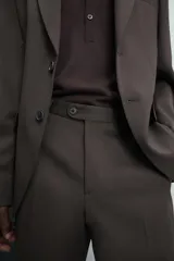 Pantalón de traje regular fit confeccionado en tejido de lana. Presenta bolsillos frontales, bolsillos traseros de vivo con botón y cierre frontal con cremallera y botón.