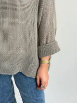 Sweater de tejido tipo waffle color visón, con cuello redondo, mangas amplias con vuelta y corte holgado.