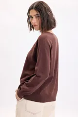 Sweater de punto fino con hilo lurex en color marrón, cuello redondo y mangas largas con hombros caídos.
