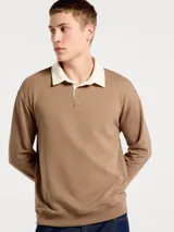 Buzo de estilo polo con cuello camisero en color crema y cuerpo en tono marrón. Presenta cierre frontal con botones, mangas largas y puños acanalados.