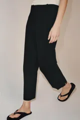Pantalón de tiro medio con cintura con trabillas, detalle de raya planchada y bajo con aberturas laterales. Cierre frontal con cremallera, botón y ganchos metálicos.
