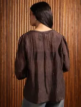 Blusa de tela liviana color bordó, con escote en V y detalles de bordado floral tono sobre tono. Presenta mangas largas con leve volumen y puños abotonados.