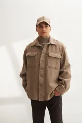 Camisa estilo leñadora marrón con diseño de espiga, cuello clásico, abrochadura frontal a la vista, bolsillos plaqué con tapa en el pecho, mangas largas con puño y botón.