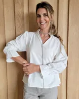 Blusa de algodón color azul, de corte suelto, con mangas largas abullonadas y cuello con volados y escote en V.