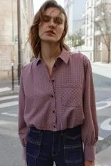 Camisa corta de manga larga con cuello solapa, confeccionada en tela con estampado de cuadros vichy en color bordó y blanco. Presenta un bolsillo delantero de plastrón, cierre frontal con botones y bajo abullonado con elástico interior.