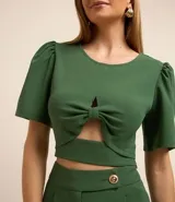Blusa cropped de crepé color verde oscuro, con cuello redondo, mangas cortas abullonadas y detalle cutout en el busto.