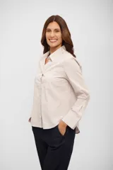 Camisa de corte clásico con cuello camisero, cierre frontal de botones y bolsillo en el pecho. Presenta un diseño de rayas verticales finas en tonos beige y blanco.