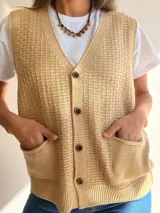 Chaleco de tejido de punto con textura, escote en V y cierre frontal con botones. Presenta dos bolsillos delanteros y terminaciones en tejido acanalado en el ruedo.