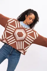 Buzo tejido de punto con diseño geométrico tipo mandala en tonos marrón, beige y blanco. Presenta cuello redondo y puños en color celeste pastel, con corte holgado y mangas largas.