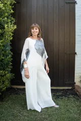 Pantalón tipo palazzo de gasa plisada en color blanco off-white. Presenta un diseño de pierna ancha, caída fluida y forro interno.