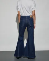 Jean de denim azul oscuro con diseño acampanado y costuras decorativas a contratono en las piernas.