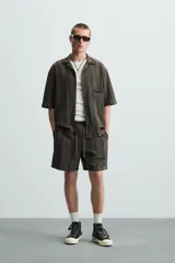 Bermuda de algodón color blanco, de corte relajado (relaxed fit), con cintura elástica ajustable mediante cordón. Posee bolsillos laterales y un bolsillo trasero de plastrón. Presenta un bordado en contraste en la pernera.