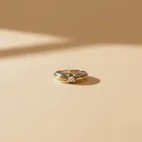 Anillo de diseño bicolor en plata y oro, con una circonia central engastada en una estructura que combina ambos metales.