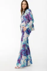 Pantalón de vestir con leve evasé y tajo en laterales, con estampado floral en tonos celeste, blanco y violeta.