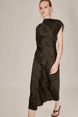 Vestido midi de corte asimétrico con escote barco, una manga corta y un hombro descubierto. Presenta un diseño drapeado en el lateral y estampado de lunares dorados sobre fondo negro.