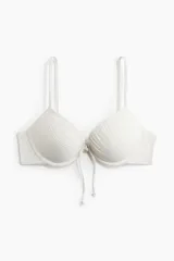 Top de bikini push-up color blanco, con aros, textura gofrada, tirantes finos dobles ajustables y un lazo decorativo en el centro del busto.