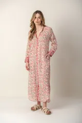 Vestido largo de manga larga, con cuello en V y cierre frontal completo. Presenta un estampado floral en tonos rosados y verdes sobre fondo blanco, con ribetes rosados en el cuello, puños y a lo largo del cierre.