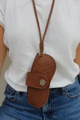 Cuelga lentes de cuero rojo con correa fina y botón metálico.