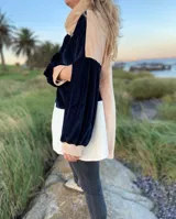 Polerón de corte holgado con mangas largas abullonadas, confeccionado en terciopelo negro con detalles en beige y blanco.