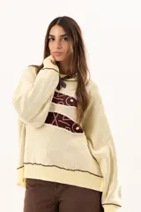 Buzo tejido de punto en color manteca, con diseño frontal de dos sardinas en color bordó. Presenta detalles bordados a mano en los bordes de las figuras y terminaciones con galón picot en cuello, puños y ruedo. Posee un corte holgado y aberturas laterales en el bajo.