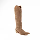 Bota estilo texana de caña media, confeccionada en gamuza color beige. Presenta un diseño slouchy con arrugas naturales, punta fina y taco cuadrado de madera. Incluye costuras decorativas en la puntera y detalles en cuero liso en la parte superior de la caña.