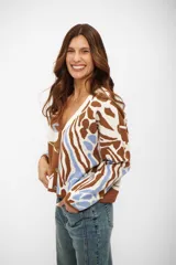 Saco de punto con escote en V y cierre frontal de botones. Presenta un diseño estampado con formas abstractas en tonos marrón, blanco y celeste.