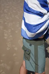 Short de baño verde con estampado de hojas y flores en tonos verde oscuro y marrón. Tiene bolsillos laterales y traseros, cintura elástica con cordón ajustable y corte clásico.