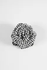 Broche en forma de flor confeccionado en tela con estampado cuadrillé en blanco y negro.
