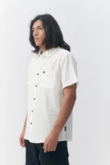 Camisa de manga corta Quiksilver modelo Robin Lisa, color blanco, de corte regular con cierre frontal de botones, cuello camisero y un bolsillo aplicado en el pecho con pequeña etiqueta de la marca.