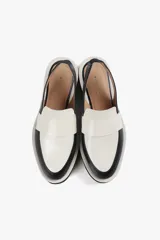 Mocasín slingback de cuero negro con detalle blanco en el empeine y base con plataforma dentada.