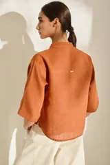 Camisa de lino color fucsia, con cuello mao, mangas cortas holgadas y cierre frontal con botones de madera. Cuenta con bolsillos frontales en el pecho.