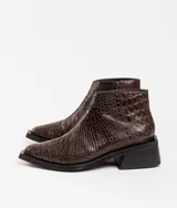 Bota corta de cuero vacuno con acabado metalizado y textura de reptil. Presenta punta fina, cierre lateral interno y taco cuadrado de madera.